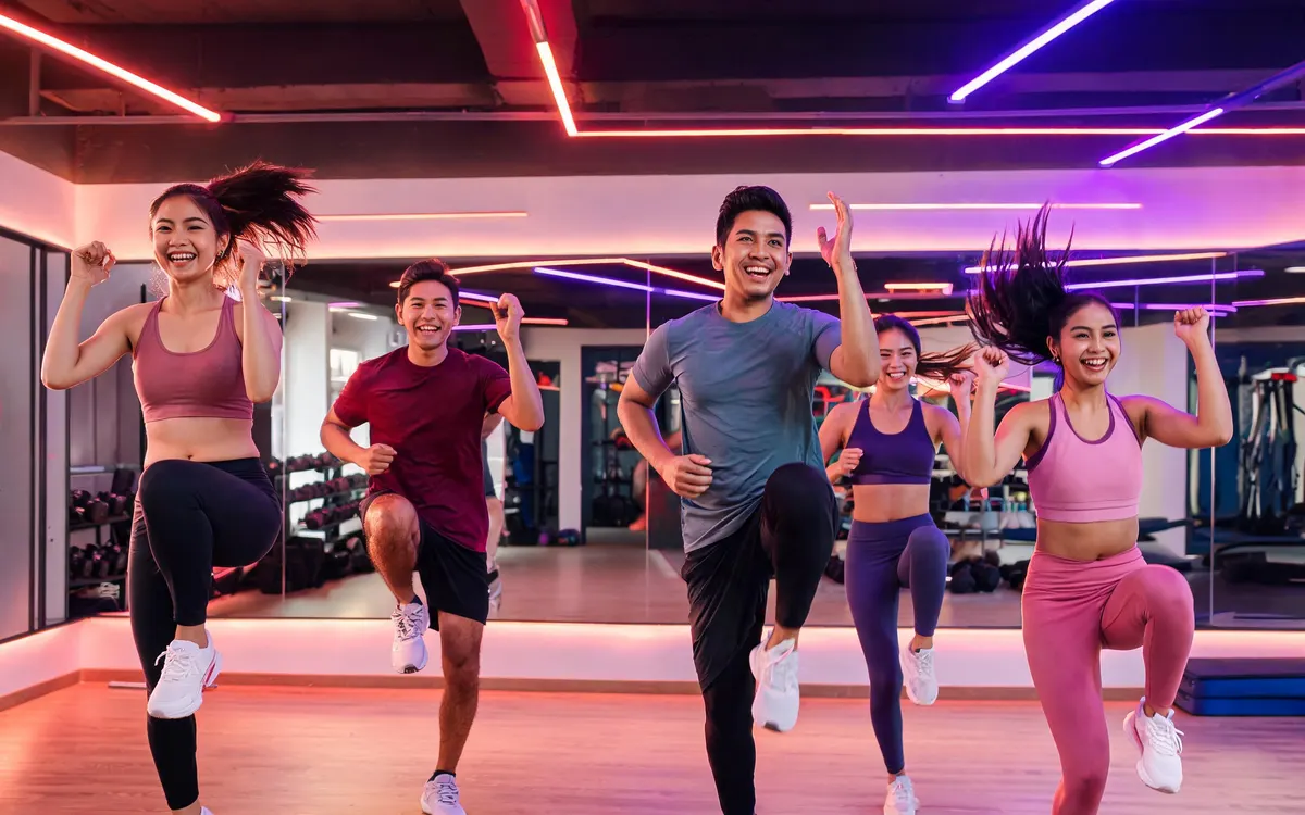 AI-generated website hero photo: energetic group fitness class in a neon-lit studio